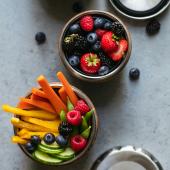 stainless steel lunch containers holding mixed berries and veggie sticks
